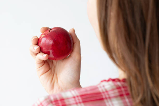A young Asian woman holding a red apple