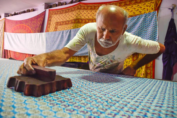 Artisan stamping patterns in ink on traditional Indian textiles as colorful saris at Jaipur. India