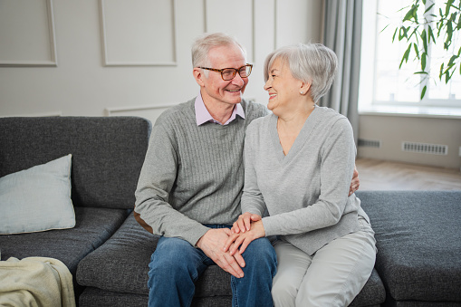 Senior adult mature couple hugging at home. Mid age old husband and wife embracing with tenderness love enjoying sweet bonding wellbeing. Grandmother grandfather together. Family moment love and care