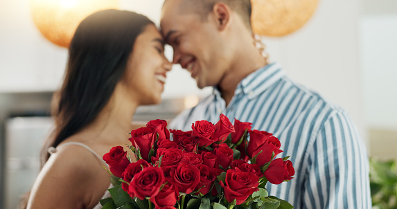 Couple, flowers and kiss for anniversary celebration, marriage and loyalty or commitment to love. People, happy and romance for relationship milestone, bonding and plant gift for support at home