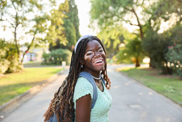 istock Young black girl student with vitiligo smiling at camera on university campus 2094659548