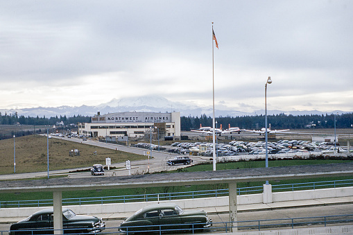 Seattle, Washington, USA - December 28, 1952: Northwest Airlines maintenance facility at the new Sea-Tac airport. Four DC-3s on tarmac. Mount Rainier hidden by clouds in background.