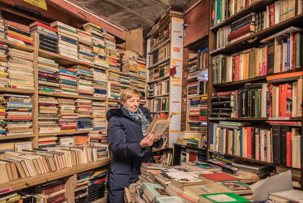 Senior Woman in an Old Bookstore in Venice, Italy Senior Woman in an Old Bookstore in Venice, Italy bookstore stock pictures, royalty-free photos & images