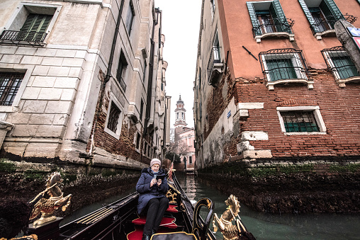 Senior Woman Enjoy the Ride Through the Canals with Gondola on Winter Day in Venice