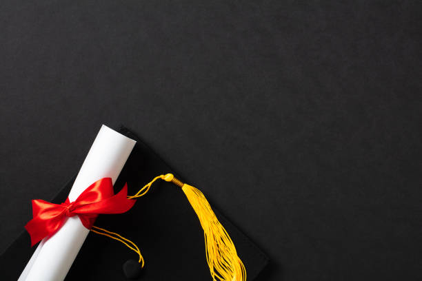 istock Graduation cap and diploma on black background. Flat lay, top view. 2094692551