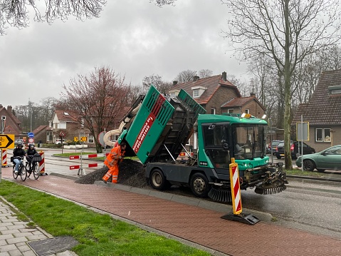 Brunssum, Netherlands - March 18,  2024.  Worker  bussy with reloading the asphalt vacuum truck during the preparation.