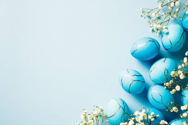 istock Happy Easter greeting card design. Flat lay dyed blue Easter eggs with flowers on pastel blue background 2094702199