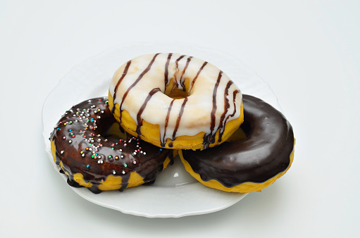 three assorted donuts on white plate, close up, isolated on white background