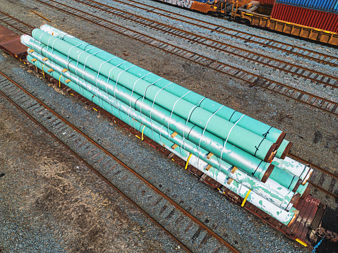 Aerial view of decommissioned pipeline segments being transported by rail.