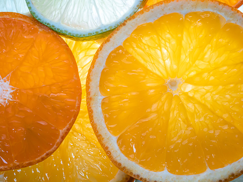 Stock photo showing close-up, elevated view of a row of citrus fruit slice wedges against a mottled grey background.