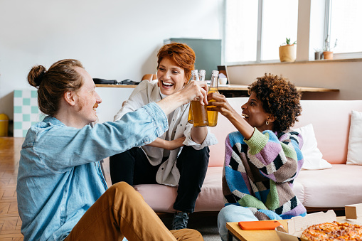 A candid moment in a bright co-working space as freelance colleagues share a toast. The casual office setting radiates a blend of productivity and comfort, reflecting modern work culture and teamwork in a shared workspace.
