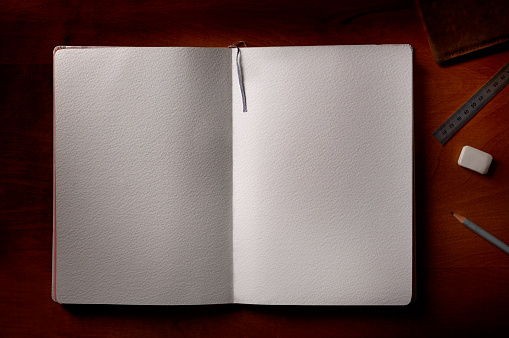 A blank notebook with a pencil and eraser on a wooden table