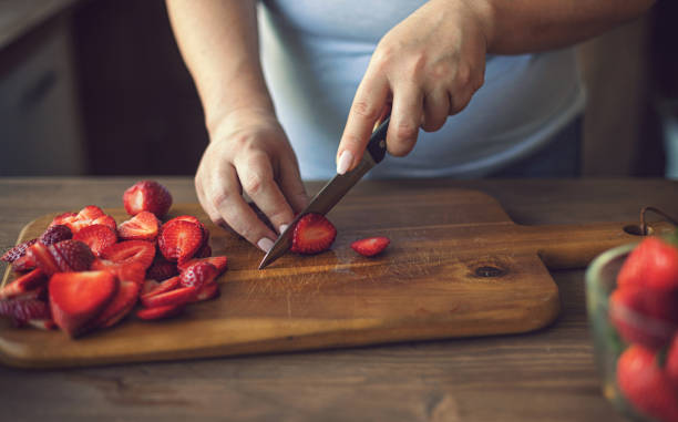 istock Young Women Cutting Fresh Strawberries 2094818206
