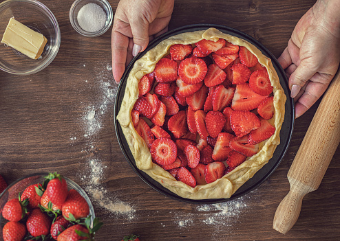 Woman preparing strawberry galette or open strawberry pie at home