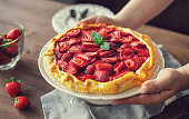 Woman serving freshly baked strawberry galette or open strawberry pie