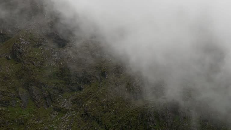 A landscape veiled in mist, featuring imposing rocks that intensify the moody tone. pano