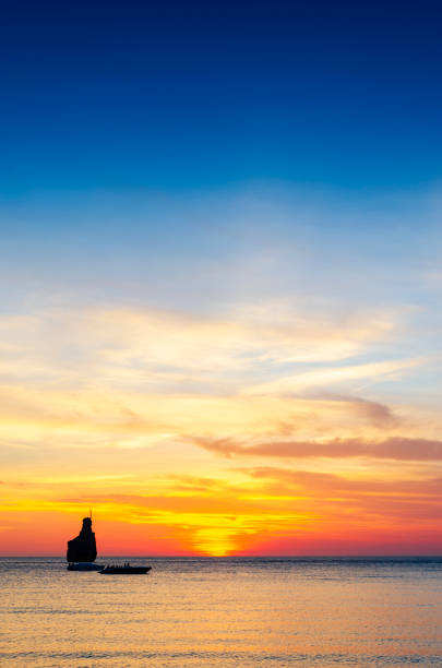 An image capturing the serene beauty of the sunset at Benirras Beach in Ibiza, where the sky transitions through a palette of vibrant colours, reflecting off the calm Mediterranean waters. This peaceful scene is a beloved spectacle, drawing visitors to experience the tranquil and magical end to the day on one of Ibiza's most iconic beaches.