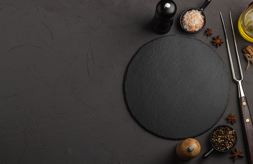 Banner Black stone plate with spices and herbs. Concept cooking. Free space for your text.