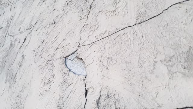 Cracked plaster. Damaged plastered, concrete wall in chips, cracks.