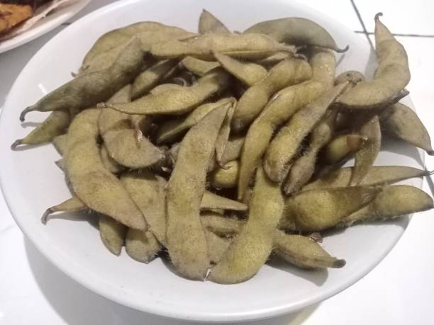 edamame sind junge sojabohnen, die sich noch in der schote befinden und in ostasiatischen gerichten zu finden sind - soybean bean edamame pod stock-fotos und bilder