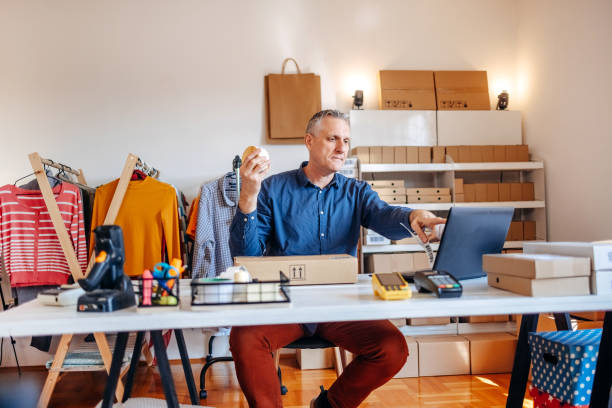istock Man packing goods and preparing it for delivery service using laptop for checking orders 2094909403