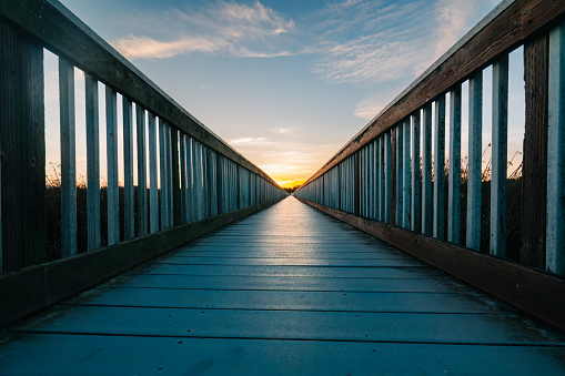 A long wooden boadwalk seems to stretch to infinity. Walkway leading to the sky at sunset, concept, copy space for the text