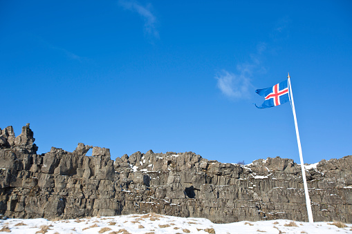 The Icelandic flag waves in front of tectonic plates in Thingvelli National Park, Iceland