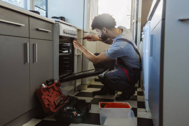 Young Latin worker repairing the oven in the kitchen