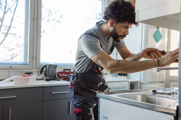 istock Hispanic plumber fixing a leak in the kitchen sink at the customer's home 2094992387
