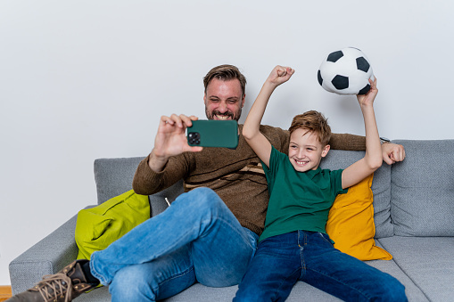 The convenience of a smartphone brings a soccer match to a father and son at home, where they engage with every play in a display of mobile fandom