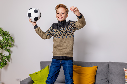 For a young boy, the living room turns into a stadium as he watches a soccer game on TV, his enthusiasm matching that of the crowd he sees on the screen