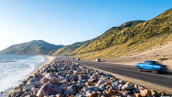 View of the PCH or Pacific Coast Highway in Malibu, California, with Point Mugu in the distance on a sunny summer afternoon. California State Route 1, also known as the PCH, runs along the coast of the Pacific Ocean in southern California.