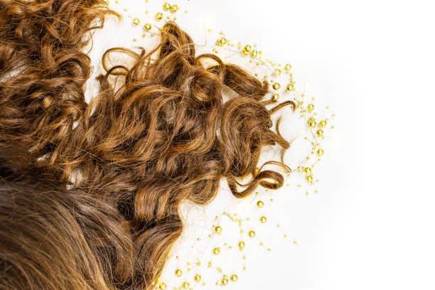 Healthy wavy female hair surrounded with garland with white yellow light on white background. Piece of brown long hair on white isolated background. Top view. Copy Space.