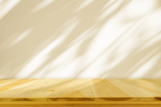 istock Empty wood table top on beige wall texture with tree leaves shadow background 2095115308