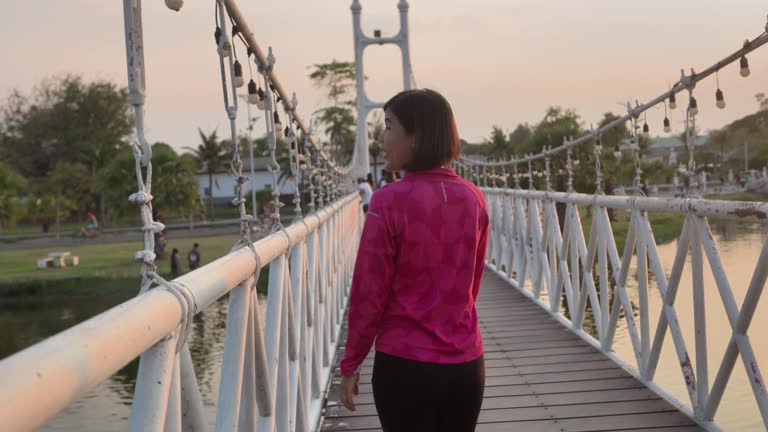 young cheerful active women sporty walking with headphones mobile phone enjoying listening to music, jogging outdoors on urban city park or forest background.