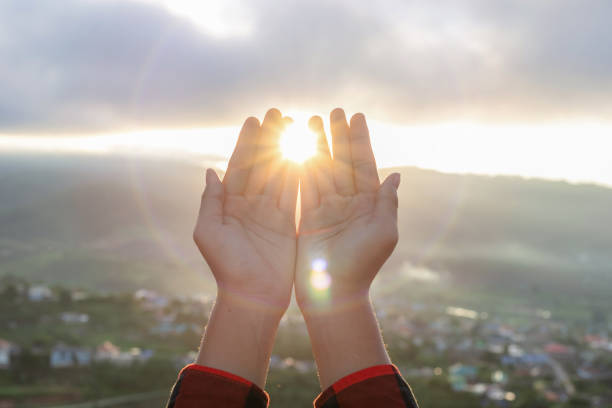 istock Human hand praying to the GOD with bright sunbeam on the sky 2095247740