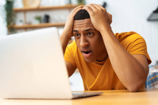 istock Frustrated, sad African American man touching head using laptop, lost money, made mistake 2095247744