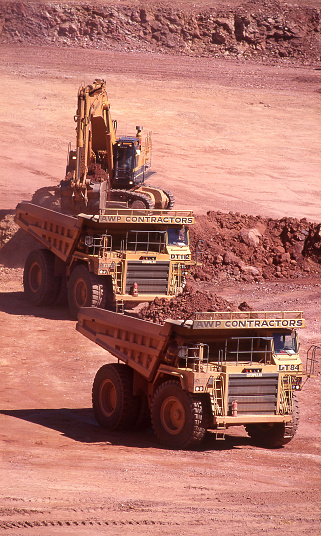 Tanami Desert, Northern Territory, Australia, Jnauary 7, 1987: Elevated view of open cut gold mine pit with heavy equipment and large dump trucks in the Northern Territory, AustraliaTanami Desert, Northern Territory, Australia, January 7, 1987: Elevated view of open cut gold mine pit with heavy equipment and large dump trucks in the Northern Territory, Australia