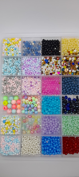close up various sizes and shaped colorful beads in transparent plastic tray isolated on white background, accessories for crafting necklaces or bracelets