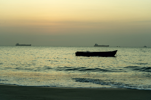 Artisanal fishing boat on the beach watching the sunset in the sea