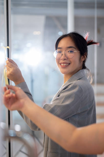 istock A creative Asian businesswoman reading some ideas on sticky notes while brainstorming with her team. 2095454253
