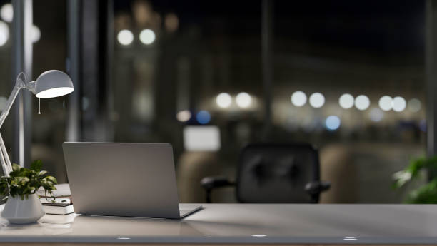 istock A laptop computer on a desk in a modern private office at night, illuminated by a table lamp. 2095465146