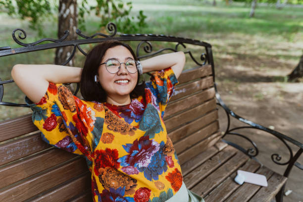 temps libre décontracté capturé alors qu’une femme souriante se détend dans le parc avec de la musique - detached house audio photos et images de collection