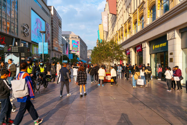 Shanghai, China - March 15th 2024: Crowds walk below neon signs on Nanjing Road. The street is the main shopping district of the city and one of the world's busiest shopping districts.