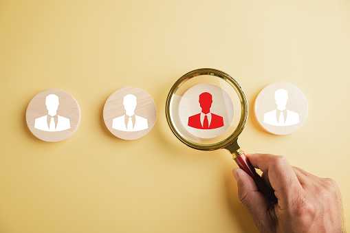 HRM concept Magnifier glass focuses on manager icon among staff icons, symbolizing human resource management's role in recruitment, leadership, and employee development. employees selection