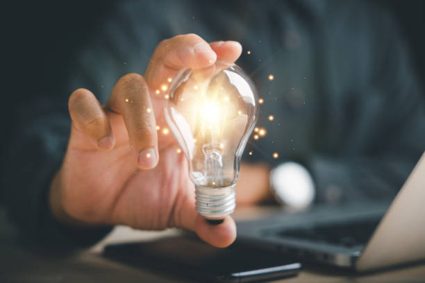 istock Businessman protects a glowing light bulb, symbolizing creativity and innovation 2095580655