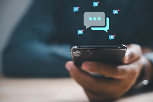 Modern communication at home man chats on smartphone, discussing live chat and social network concepts. Chat box icons appear, symbolizing digital interaction. Social media marketing technology