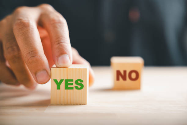 istock Businessman's hand gestures to two wooden cubes indicating check marks for right and wrong. Choice and validation communication portrayed. Think With Yes Or No Choice. 2095582777