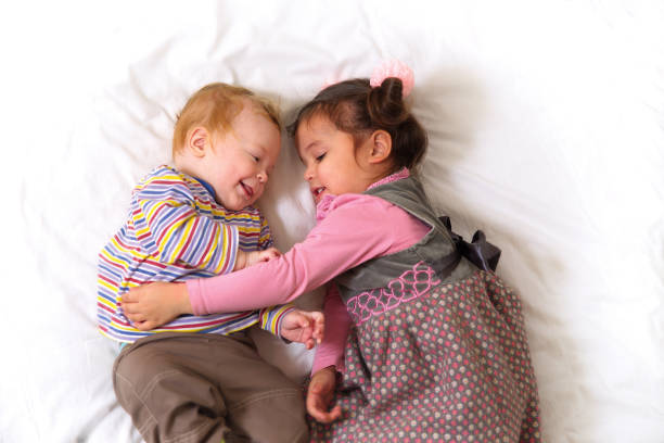 A smiling young sister and brother hug each other.