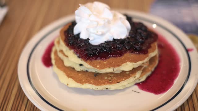 Top View Of Pancakes with Blue berries, Whipped Cream and berries sauce On Table. Closeup